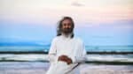 Gurudev smiling on a beach during sunset